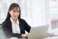 Beautiful Asian businesswomen wearing a black suit sitting in the office, smiling confidently and looking at the camera while typi Royalty Free Stock Photo