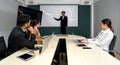 Asian businessman in black suit pointing at multicolor chart on presentation monitor. Business executives team meeting at night in