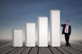 Asian businessman in black suit standing next to bar chart