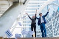 Asian businessman and businesswoman throwing paper in the air and raising up two hands to cheerful and celebrated for successful Royalty Free Stock Photo