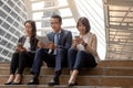 Asian businessman and businesswomen discussing ideas with digital mobile phone while sitting at the stairs Royalty Free Stock Photo