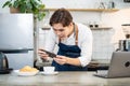 Asian businessman cafe owner take photo of cup of coffee for marketing. Young barista man restaurant worker use laptop computer