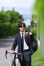 Businessman checking time on his wrist watch and commuting to work with bicycle. Royalty Free Stock Photo