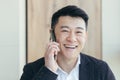 Asian businessman close-up portrait, successful and happy smiling talking on the phone, in a business suit Royalty Free Stock Photo