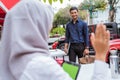 Asian businessman comes on foot as veiled woman sits waving