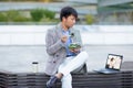 Asian businessman enjoys salad while watching webinar on laptop outdoor