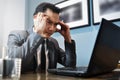 Asian Businessman in grey suit thinking and looking to his laptop. Man has stressed and headache from migraine. Royalty Free Stock Photo