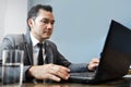 Asian Businessman in grey suit using and looking to laptop at hi Royalty Free Stock Photo