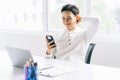 Asian businessman is leaning back in his chair and using the phone during the break Royalty Free Stock Photo