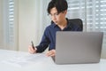 Asian businessman, male businessperson writing on paperwork with computer laptop on desk at office. Professional entrepreneur Royalty Free Stock Photo