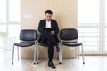 Asian businessman man, in the waiting room sitting on a chair near the reception of the office center, and fills out a test form Royalty Free Stock Photo