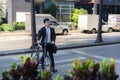 Asian businessman pushes a bicycle across a crosswalk on a city street during a morning commute