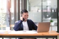 Asian businessman sitting on the phone with a customer with a laptop and document at his office desk. Royalty Free Stock Photo