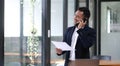 Asian businessman sitting on the phone with a customer with a laptop and document at his office desk. Royalty Free Stock Photo