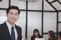 asian businessman smiling at camera while colleagues have meeting at office. business people working with co worker team Royalty Free Stock Photo