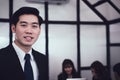 asian businessman smiling at camera while colleagues have meeting at office. business people working with co worker team Royalty Free Stock Photo