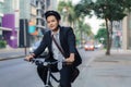 Asian businessman in a suit is riding a bicycle on the city streets for his morning commute to work. Eco Transportation Concept Royalty Free Stock Photo
