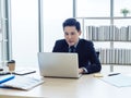 Asian businessman in suit sitting at table and working on laptop computer in office. Royalty Free Stock Photo