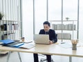 Asian businessman in suit sitting at table and working on laptop computer in office. Royalty Free Stock Photo