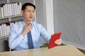Asian businessman telling someone through online video chat from tablet and have a sore throat in office