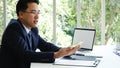 Asian Businessman using laptop at office desk. Man hands typing computer keyboard reading financial graph chart Planning analyzing Royalty Free Stock Photo