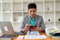 Asian businessman using smartphone and working at office desk using laptop and talking on mobile phone, Royalty Free Stock Photo