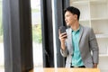 Asian businessman using smartphone and working at office desk using laptop and talking on mobile phone, Royalty Free Stock Photo