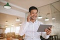 Asian businessman using a tablet and talking on his cellphone Royalty Free Stock Photo