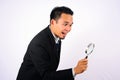 Asian Businessman very happy looking through a magnifying glass isolated on white