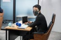 Asian businessman wearing face shield looking at camera and working with laptop and piggy bank, dumbell, cart and notebook at desk Royalty Free Stock Photo