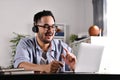 Asian businessman wearing headset on video call with clients on laptop. Young Asian man in glasses giving online educational class Royalty Free Stock Photo