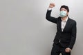Asian businessman wearing surgical face mask in formal black suit jacket, felling happy and raise hand up, sucessful