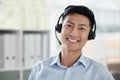 Asian businessman working in a call center and smiling in a bright office. Financial advisor wearing a headset. Customer Royalty Free Stock Photo