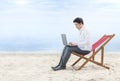 Asian businessman working with laptop sitting in the beach chair on beach Royalty Free Stock Photo