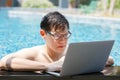 Asian businessman working with laptop in swimming pool. work new normal. lifestyle travel in holiday vacation. Royalty Free Stock Photo