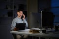 Asian businessman working late in office, talking on phone while checking documents Royalty Free Stock Photo