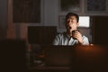 Asian businessman yawning in a dark office late at night