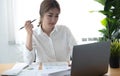 Asian businesswoman analyzes charts using laptop calculator at the office. Royalty Free Stock Photo