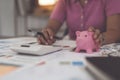 Asian Businesswoman calculating saving account balance with calculator, account and saving concept