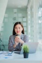 Asian businesswoman holding a cup of coffee working on investment projects and financial accounting planning strategies. Businessm Royalty Free Stock Photo