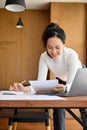 Asian businesswoman leaning working on her office desk, examining her business report Royalty Free Stock Photo