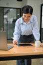 Asian businesswoman leaning working at her office desk, using digital tablet Royalty Free Stock Photo