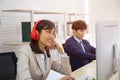 An Asian businesswoman is listening to music from his headphones in the office and the men sit seriously Royalty Free Stock Photo
