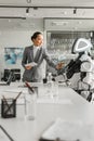 Asian businesswoman operating robot while holding