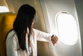 Asian businesswoman on the plane, checking a landing time on her smart watch, worry about airplane landing time Royalty Free Stock Photo