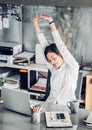 Asian businesswoman raise arm up stretching in front of desk fro