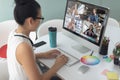 Asian businesswoman sitting at desk using computer having video call with group of colleagues Royalty Free Stock Photo