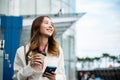 Asian businesswoman with smartphone and cup coffee standing against street building near office Royalty Free Stock Photo