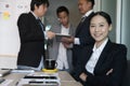 Asian businesswoman smiling at camera while colleagues have meet Royalty Free Stock Photo