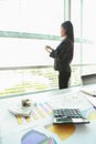 Businesswoman standing infront of window with office desk